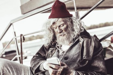 Yaşlı adam telefonun karmaşık özelliklerini anlamaya çalışan.