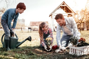 Father with his children laughing during gardening clipart