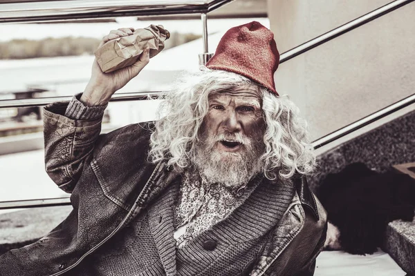 Male beggar showing paper bag he found. — Stock Photo, Image