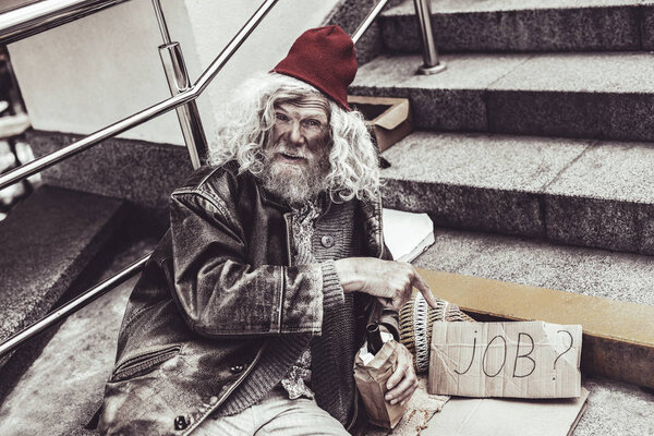 Abandoned mendicant offering his services with cardboard.