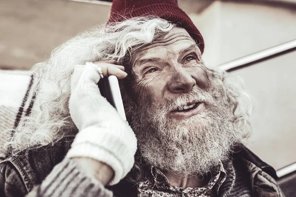 Dakloze ouderen kijken naar mensen en beschrijven aan vriend aan de telefoon. — Stockfoto