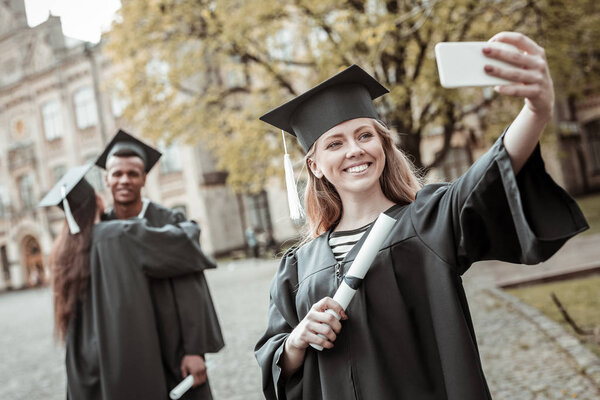 Positive delighted blonde student doing selfie photo