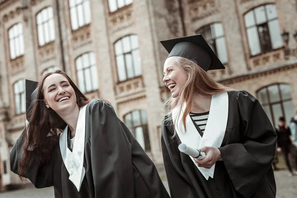Радостные девушки веселятся, стоя рядом с университетом — стоковое фото