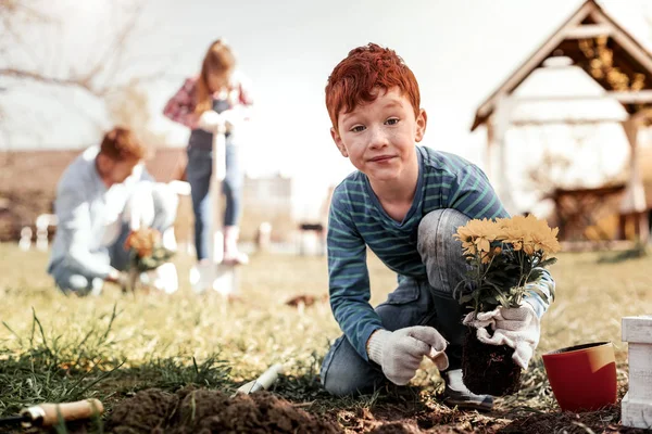 Undrar pojke med fräknar förvånande eftersom plantering första gången själv — Stockfoto