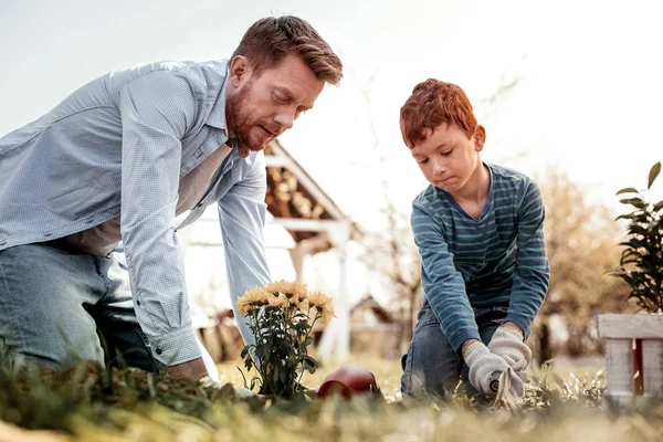 Serious impresionante niño ayudando a su padre en la jardinería — Foto de Stock