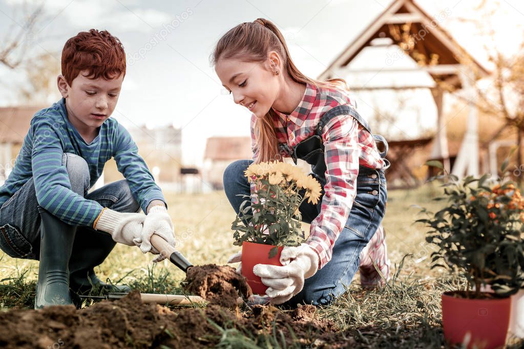 Elder red-haired sister and small brother gardening in free time