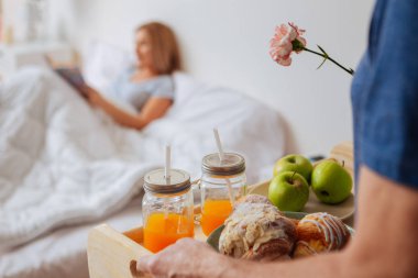 Kahvaltı ile taşıma tepsi ve küçük kenarındaki çiçek dolu vazolar kocası