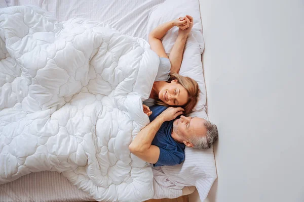Hombre y mujer se sienten relajados mientras están acostados en la cama por la mañana — Foto de Stock