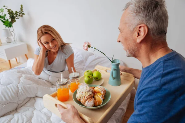 Fru tittar man håller bricka med frukost och blommor — Stockfoto