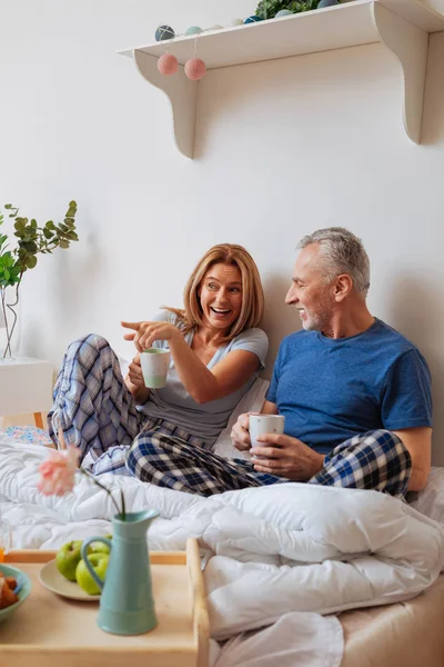 Esposo y esposa relajándose en la cama mientras beben café — Foto de Stock