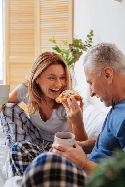 Férj és feleség élvez finom croissant és kávé az ágyban — Stock Fotó