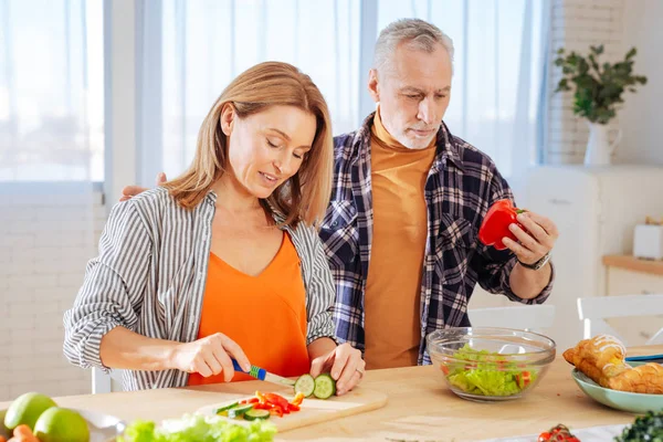 Чоловік стоїть біля своєї дружини готує салат на вечерю — стокове фото