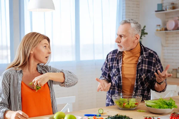 Блондинка эмоциональная жена бросает кусок салата в своего мужа — стоковое фото