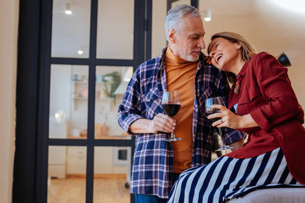 Cheerful laughing wife leaning on shoulder of her husband