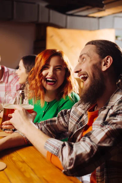 Сияющая рыжеволосая девушка пьет пиво со своим мужчиной — стоковое фото