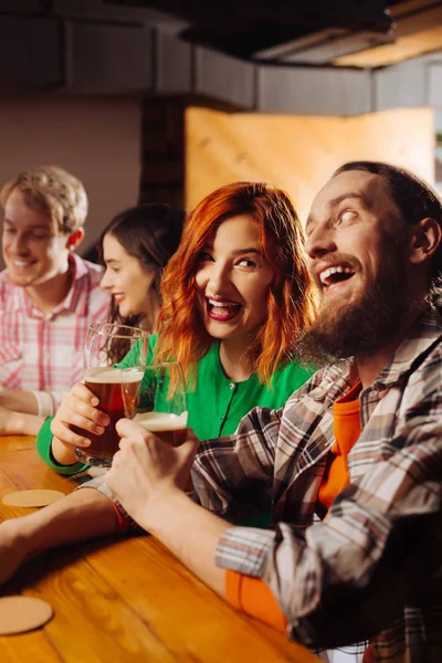 Pareja divertida colgando vasos con cerveza en el pub el viernes por la noche — Foto de Stock