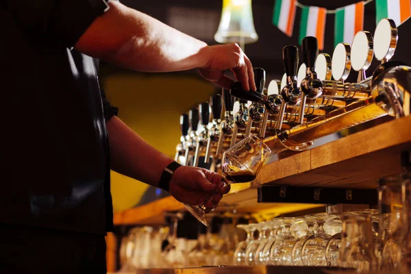 Barman nosit jednotný pracovní tvrdé nalil pivo pro jeho návštěvník — Stock fotografie