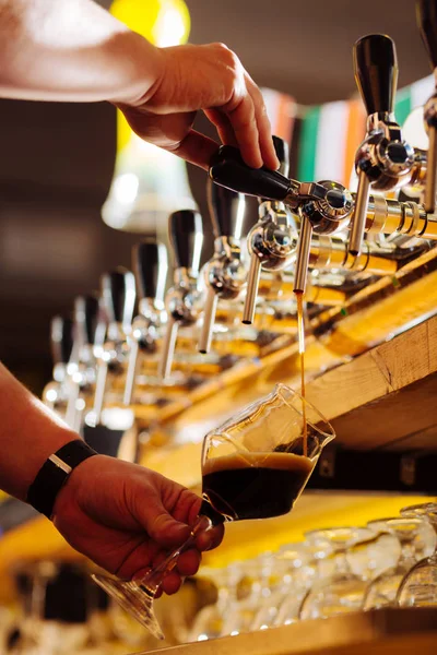 Zblízka barman vylévající kvalitní tmavého piva do pěkné sklenice — Stock fotografie