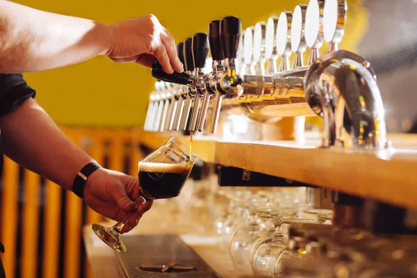 Бармен носіння руки дивитися розливу пива в скло — стокове фото