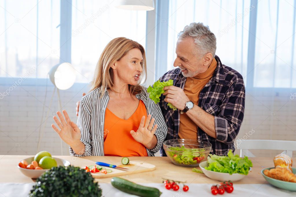 Husband calming his overemotional wife while cooking salad