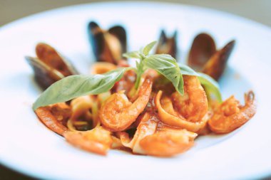 Geniş beyaz tabakta domates sosu ve deniz ürünleri adet makarna