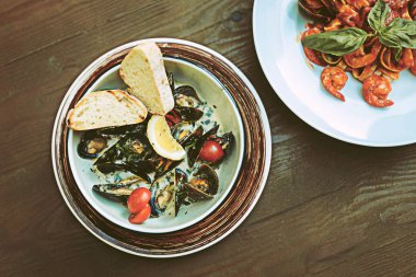 Ahşap masaya yakın duran sulu yakışıklı deniz ürünleri yemekleri