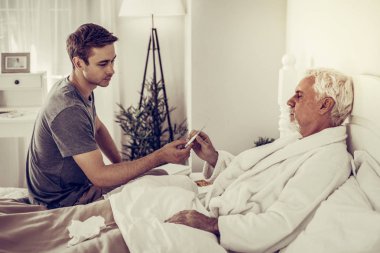 Genç-Yetişkin oğlu termometre yaşlı hasta babasına teslim