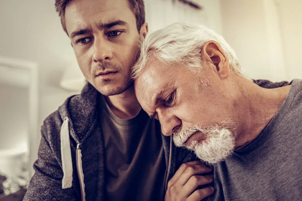 Aging man hoofd leunend op de schouders van zijn zoon — Stockfoto