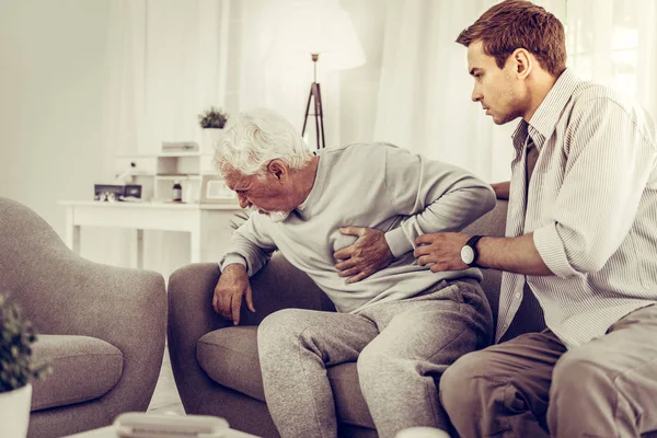 Shocked son trying to help father with a heart attack. — Stock Photo, Image