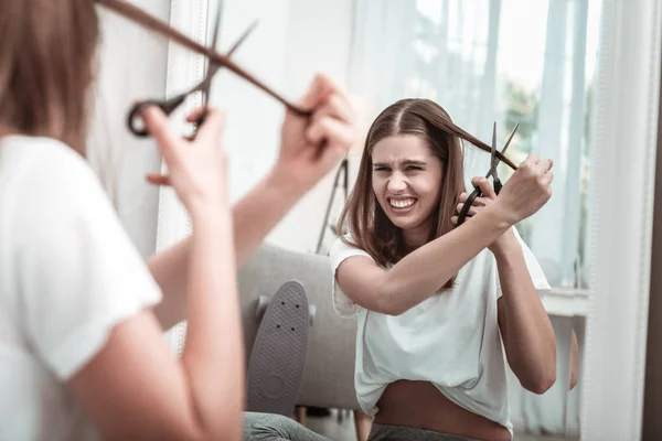 Genervte Frau beim Versuch, sich die Haare zu schneiden — Stockfoto