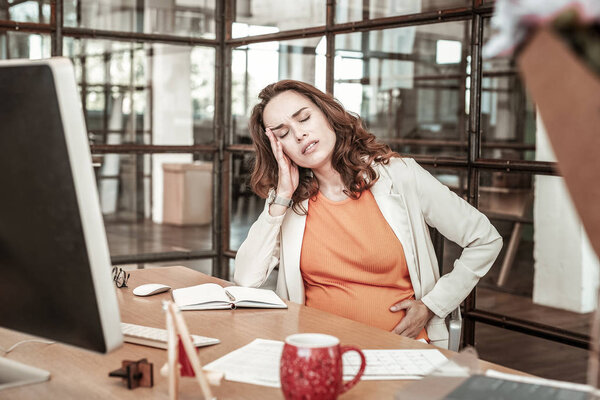 Уставшая темноволосая женщина беспокоится о своем здоровье
