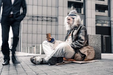 Sefil gri saçlı yaşlı evsiz olduğu soğuk yerde oturan