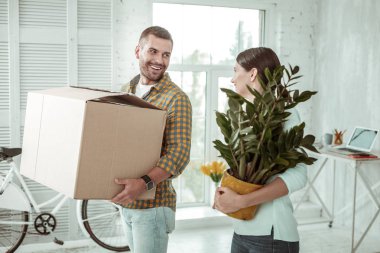 Yeşil bir bitki tutan neşeli genç kadın