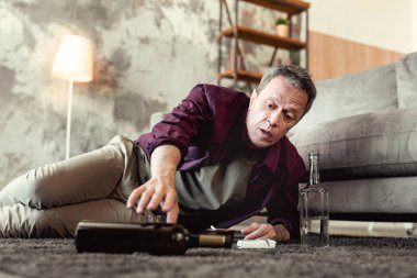 Şişe şarap uzanarak umutsuz gri saçlı adam