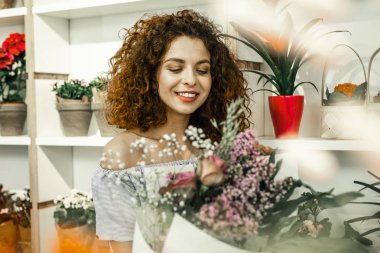 Güzel yaratıcı çiçek kompozisyonlar üzerinde çalışan kıvırcık saçlı çiçekçi