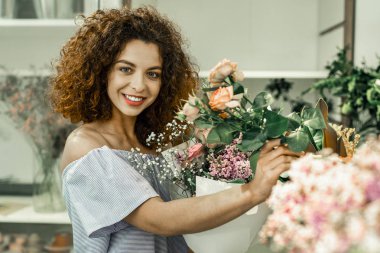 Çizgili önlük duygu ikebana yaparken meşgul giyen kıvırcık kadın
