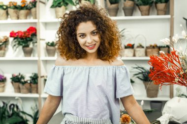 Neşeli ışınlama çiçekçi güzel buketler ayakta çizgili önlük giyiyor