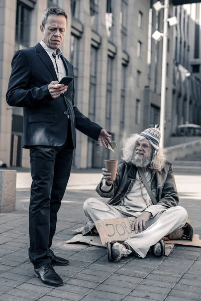 Nette zakenman in kostuum geld steken in koffiekopje — Stockfoto