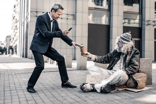 Vain rich man making selfie of himself with dirty homeless — Stock Photo, Image