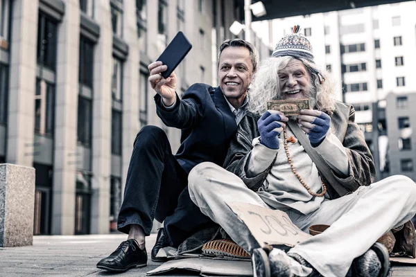 Marné bohatý muž v kostýmu takže selfie darování peněz — Stock fotografie