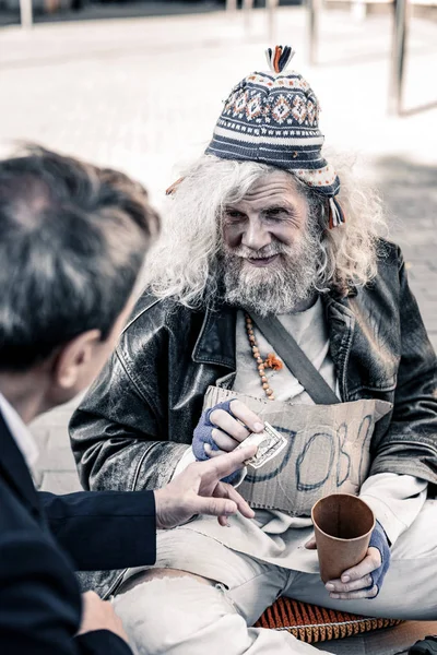 Hombre rico participando en actos de caridad mientras entrega dinero a personas sin hogar —  Fotos de Stock