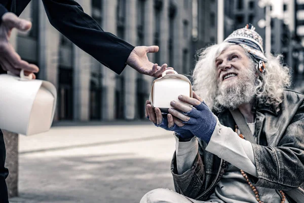 Alegre homem pobre de cabelos longos sendo animado ao receber caixa com comida — Fotografia de Stock