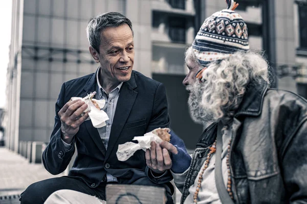 Communicative kind man talking to grey-haired senior homeless