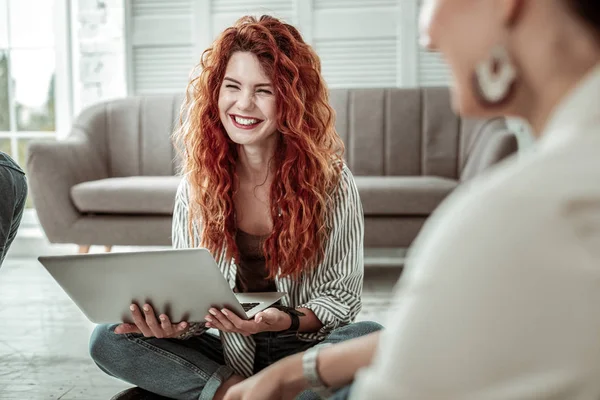 Positive red haired woman sitting with her laptop