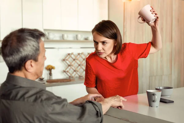 Risoluta donna arrabbiata in t-shirt rossa lanciando tazza vuota — Foto Stock