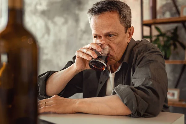 Apathique homme aux cheveux gris sirotant de l'alcool du verre — Photo