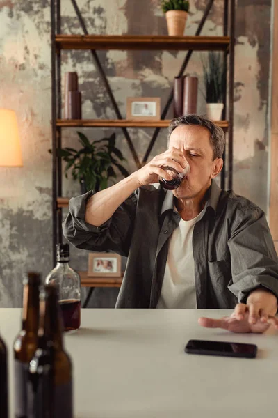Взрослый мужчина плохо выглядит, когда сидит в одиночестве и пьет алкоголь — стоковое фото