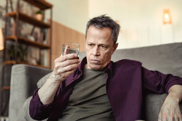 Schwer depressiver Mann beobachtet Alkohol im Glas und denkt tief nach — Stockfoto