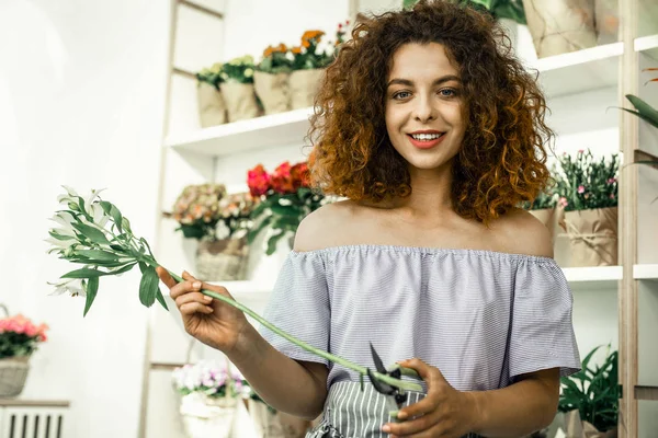 Young curly student enjoying her part-time job in flowershop — Stock Photo, Image