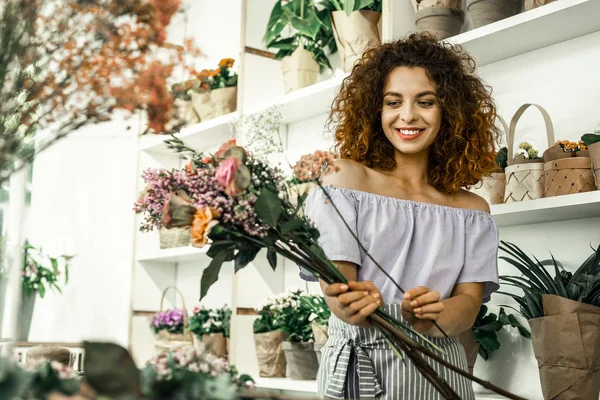 Женщина, работающая в цветочном магазине, взволнована составлением букета — стоковое фото